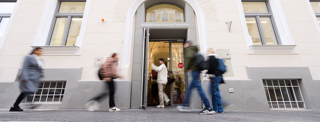 Personen gehen in den Eingang des Caritas Ausbildungszentrums Seegasse